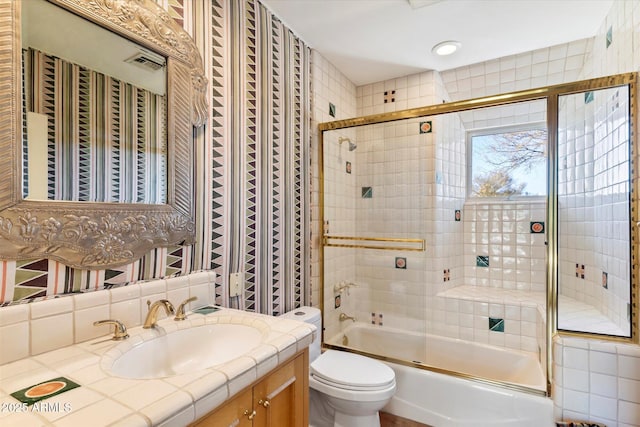 full bathroom featuring bath / shower combo with glass door, toilet, and vanity