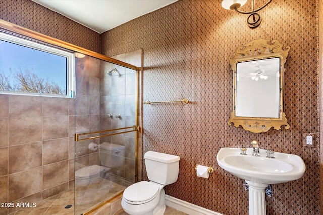 bathroom with toilet, ceiling fan, and an enclosed shower