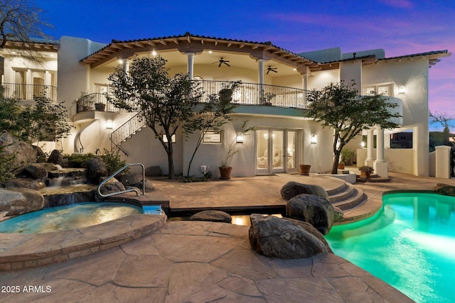 pool at dusk featuring ceiling fan, a patio area, and an in ground hot tub