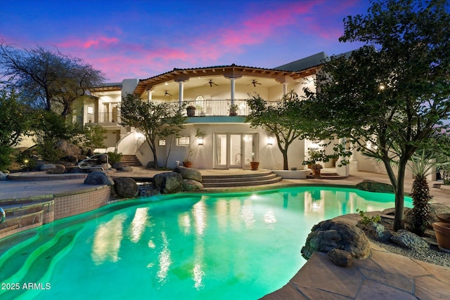 pool at dusk with ceiling fan and a patio