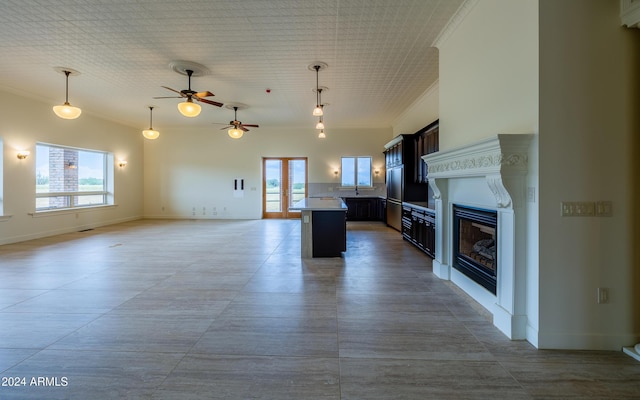 kitchen with a center island, ceiling fan, ornamental molding, decorative light fixtures, and dark brown cabinetry