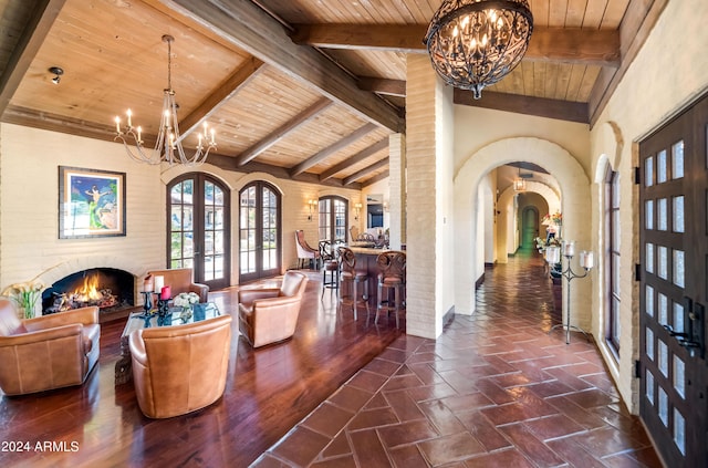 interior space with beam ceiling, wooden ceiling, high vaulted ceiling, a notable chandelier, and a fireplace