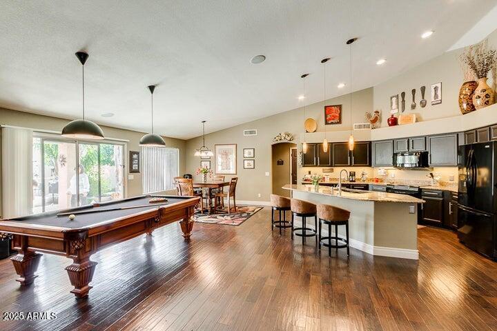 game room with lofted ceiling, sink, and dark wood-type flooring