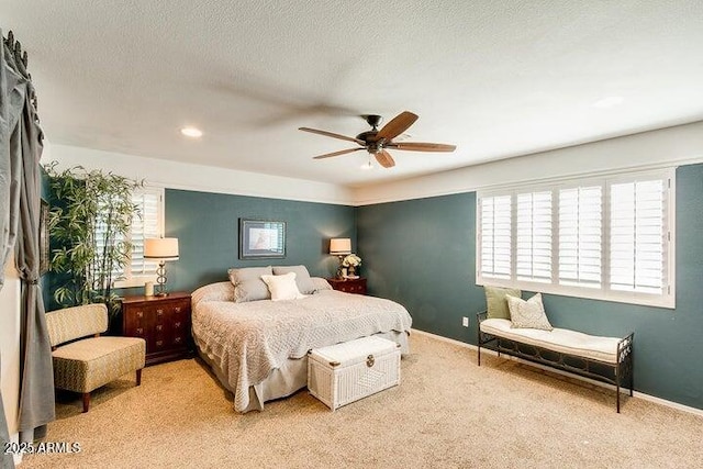 bedroom featuring ceiling fan, light colored carpet, and a textured ceiling