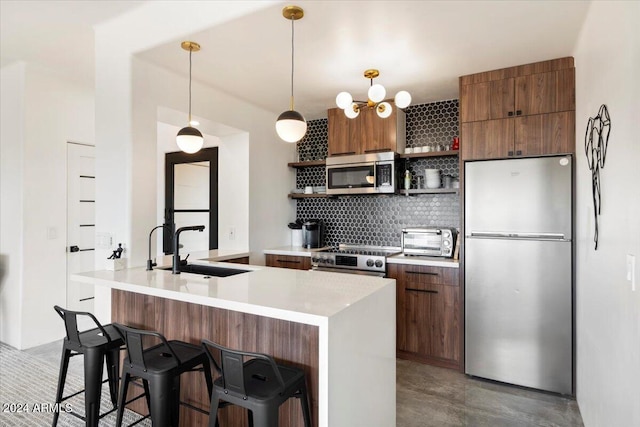 kitchen with decorative light fixtures, backsplash, appliances with stainless steel finishes, and a breakfast bar area