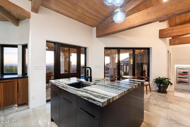 kitchen with a center island with sink, beam ceiling, sink, a high ceiling, and wood ceiling