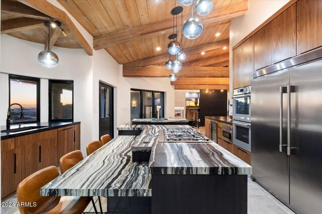 kitchen with a spacious island, appliances with stainless steel finishes, wood ceiling, a kitchen bar, and sink