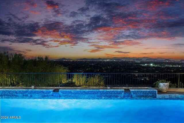 pool at dusk featuring pool water feature