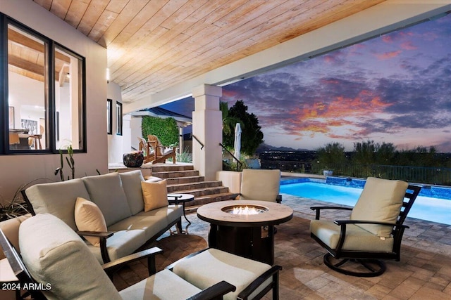 patio terrace at dusk with pool water feature, an outdoor living space with a fire pit, and a fenced in pool