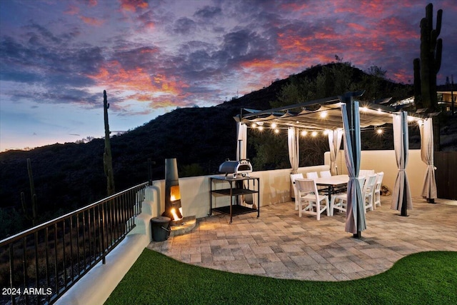 patio terrace at dusk featuring a mountain view and exterior kitchen