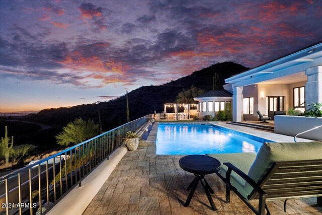 pool at dusk with a patio area and a mountain view