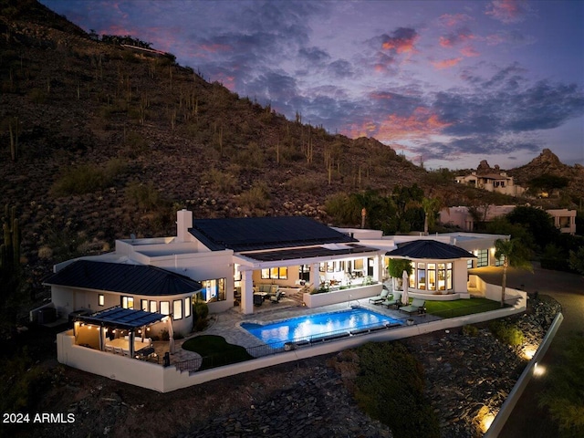 back house at dusk featuring a patio area and outdoor lounge area