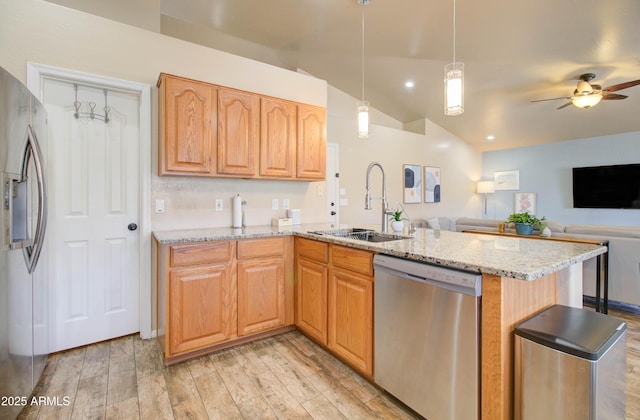 kitchen with light wood-type flooring, a sink, stainless steel appliances, light stone countertops, and vaulted ceiling