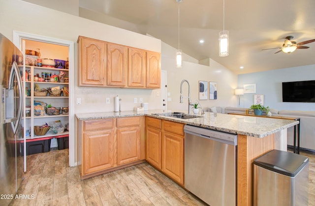 kitchen featuring light wood-style flooring, a sink, stainless steel appliances, light stone countertops, and vaulted ceiling