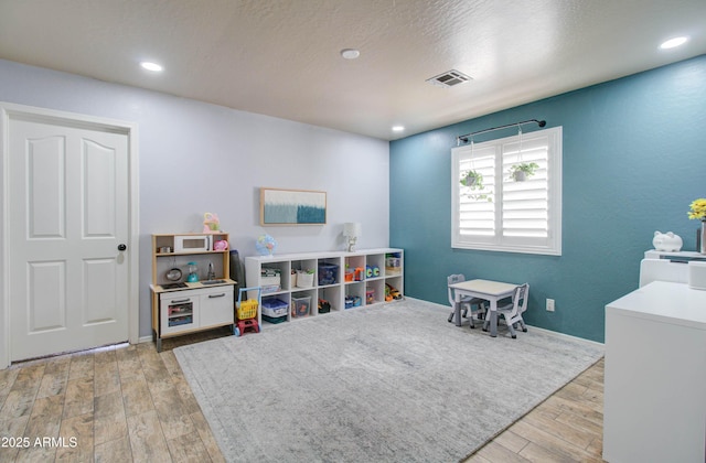 rec room with recessed lighting, wood finished floors, visible vents, and a textured ceiling