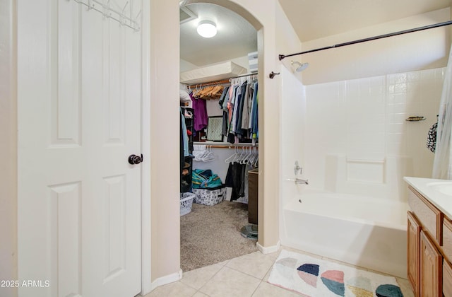 bathroom featuring tile patterned flooring, a walk in closet, shower / tub combination, and vanity