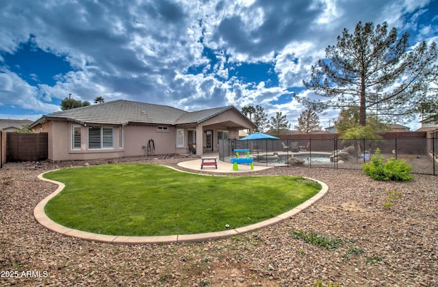 rear view of property featuring a fenced in pool, a fenced backyard, stucco siding, a tile roof, and a patio area