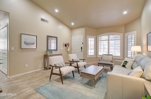 living room featuring visible vents, baseboards, vaulted ceiling, recessed lighting, and light wood-style floors