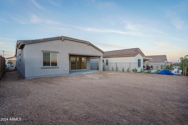 back house at dusk with a patio area