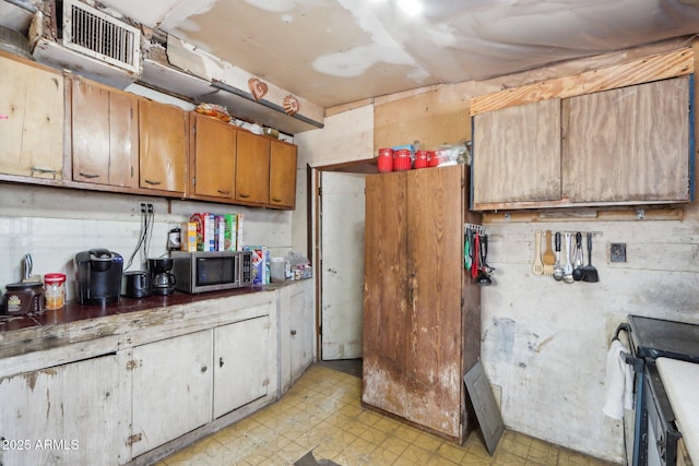 kitchen with electric range, visible vents, brown cabinets, light floors, and stainless steel microwave