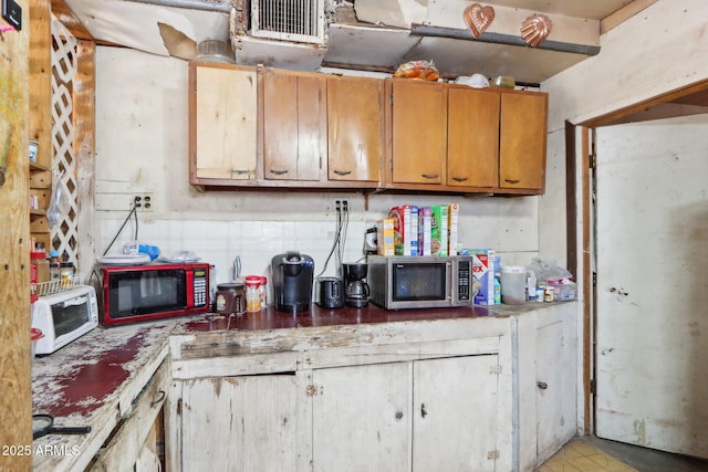 kitchen with light countertops, white microwave, stainless steel microwave, and brown cabinets