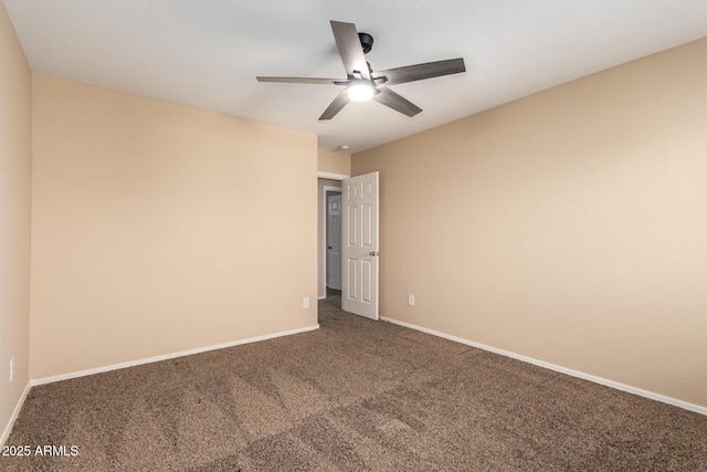 spare room featuring ceiling fan and dark carpet