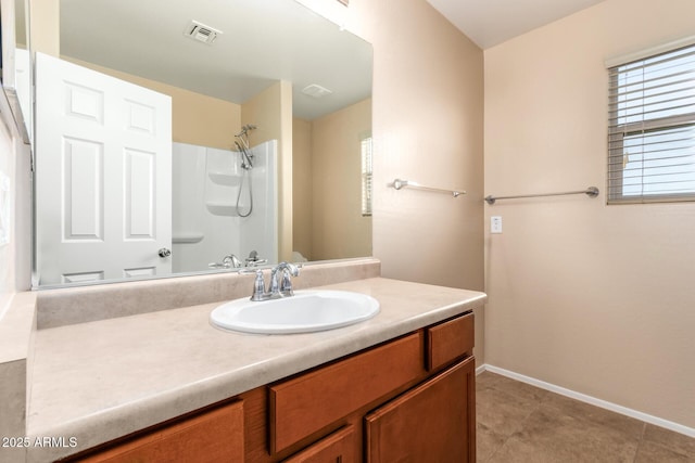 bathroom featuring tile patterned flooring, vanity, and a shower