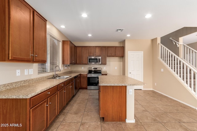 kitchen featuring sink, light tile patterned floors, a kitchen island, and appliances with stainless steel finishes