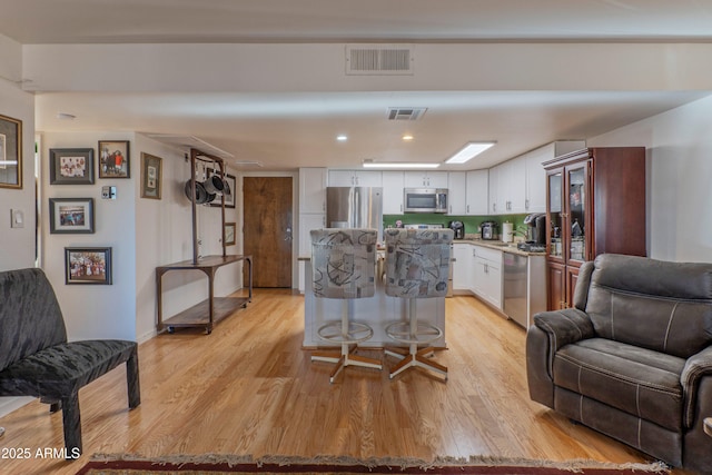 interior space featuring visible vents, white cabinets, light wood-style flooring, stainless steel appliances, and light countertops