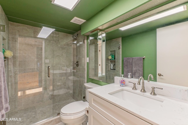 bathroom with a stall shower, visible vents, vanity, and toilet