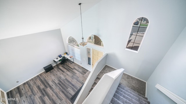 staircase featuring high vaulted ceiling and dark wood-type flooring