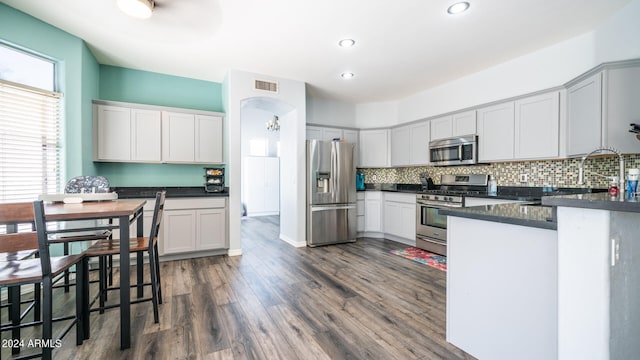 kitchen featuring appliances with stainless steel finishes, a wealth of natural light, tasteful backsplash, and hardwood / wood-style flooring