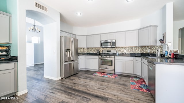 kitchen featuring tasteful backsplash, decorative light fixtures, dark hardwood / wood-style flooring, sink, and appliances with stainless steel finishes