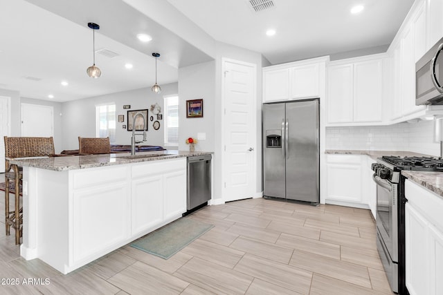 kitchen featuring sink, decorative light fixtures, stainless steel appliances, light stone countertops, and white cabinets