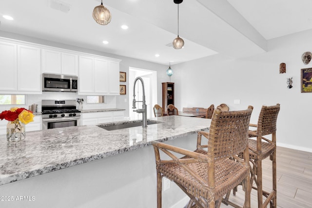 kitchen with white cabinetry, appliances with stainless steel finishes, light stone countertops, and sink