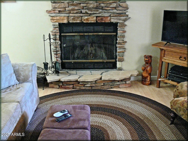 living room with hardwood / wood-style flooring and a stone fireplace