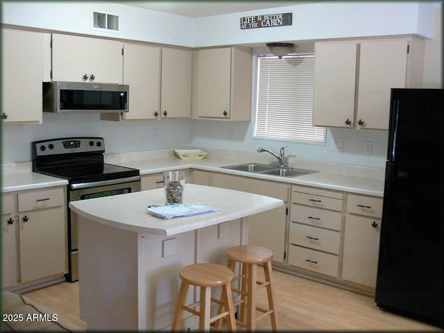 kitchen with sink, a center island, a kitchen breakfast bar, light hardwood / wood-style floors, and appliances with stainless steel finishes