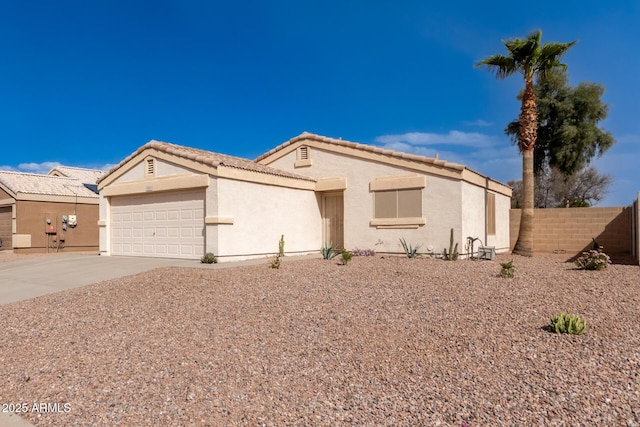 view of front of property featuring stucco siding, fence, a garage, driveway, and a tiled roof