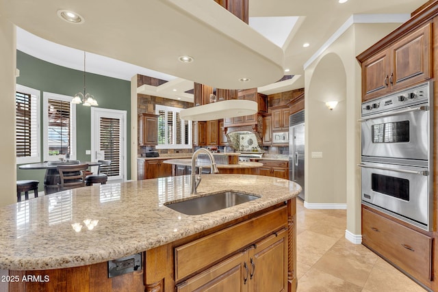 2371 E Sanoque Ct, Gilbert, AZ 85298 - kitchen featuring appliances with stainless steel finishes, a center island with sink, a chandelier, tasteful backsplash, and light stone countertops