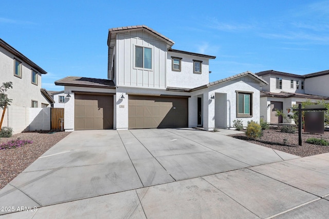 modern inspired farmhouse featuring fence, stucco siding, concrete driveway, a garage, and board and batten siding