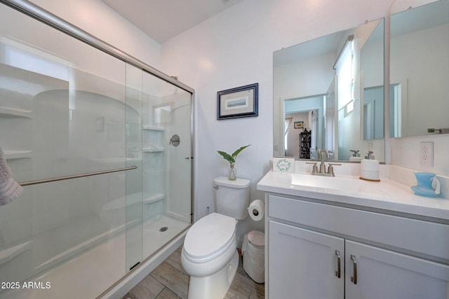 bathroom with a stall shower, toilet, vanity, and wood finished floors