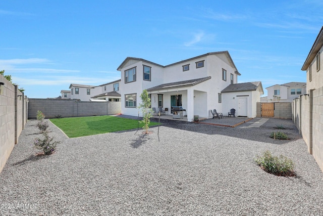 rear view of property with stucco siding, a lawn, a fenced backyard, a patio, and a gate