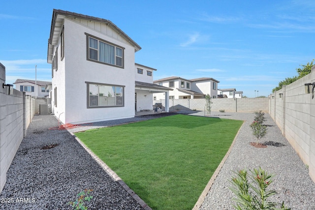 back of house featuring a patio, a yard, a fenced backyard, central AC, and stucco siding