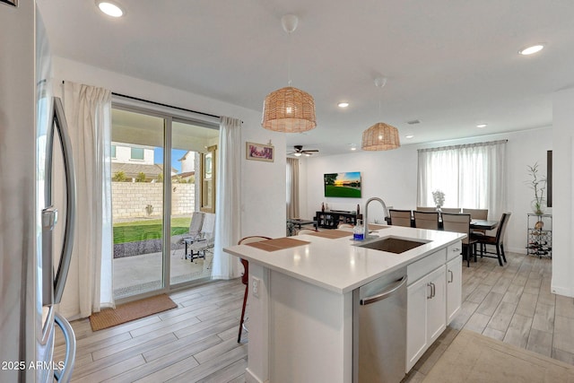 kitchen with wood finish floors, a sink, white cabinetry, appliances with stainless steel finishes, and light countertops