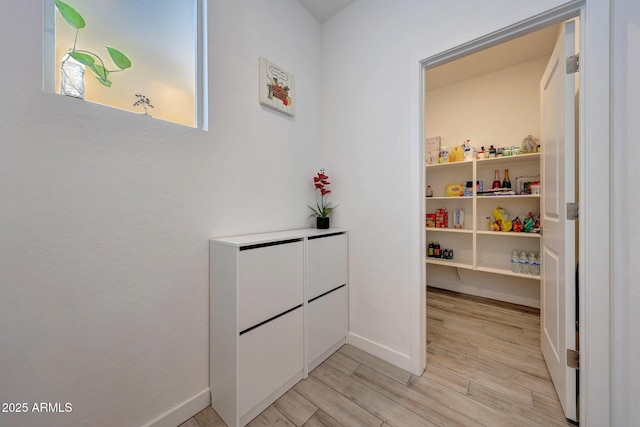 corridor featuring light wood-style flooring and baseboards