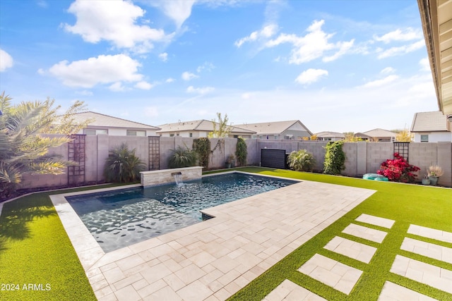 view of swimming pool with pool water feature, a yard, and a patio