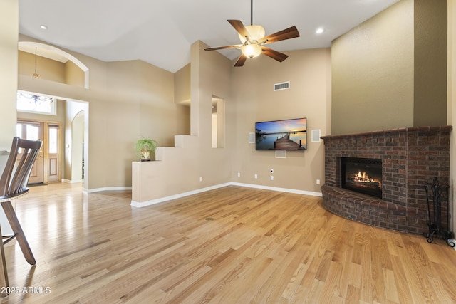 unfurnished living room with light wood-type flooring, high vaulted ceiling, baseboards, and visible vents