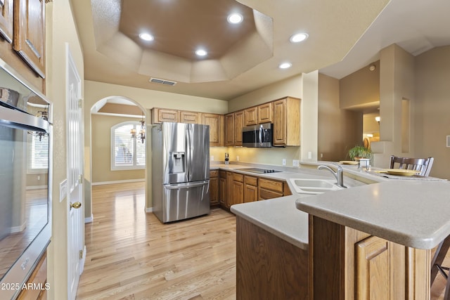 kitchen featuring a peninsula, stainless steel appliances, a sink, visible vents, and light countertops