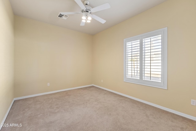 spare room featuring light carpet, ceiling fan, visible vents, and baseboards