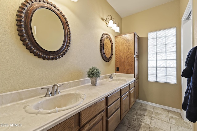 bathroom with double vanity, tile patterned floors, a sink, and baseboards